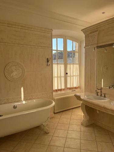 une grande salle de bain avec une baignoire et un lavabo dans l'établissement Hôtel de Margaux, à Margaux
