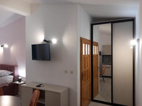 a room with a bed and a television on a wall at Mitan apartman in Tučepi