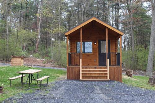 a wooden cabin with a picnic table and a bench at The Bellefonte Campground in Bellefonte