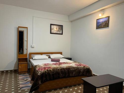 Pradhan Homestay Mirik - Homestay beside Mirik Lake في Mirik: غرفة نوم فيها سرير وطاولة فيها