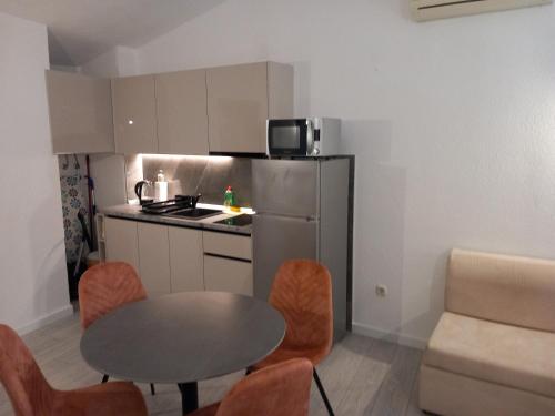 a small kitchen with a table and a table and chairs at Mitan apartman in Tučepi
