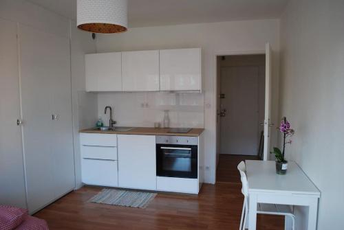 une cuisine avec des placards blancs, une table et un comptoir dans l'établissement Petite France, Studio de charme vue sur l'Ill, à Strasbourg