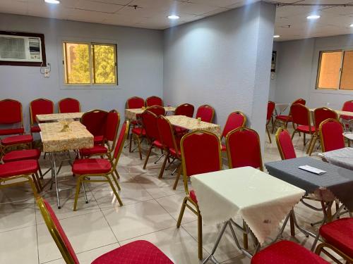 a dining room with tables and chairs and red chairs at Najmat Alnoor Almaabdah Hotel in Makkah