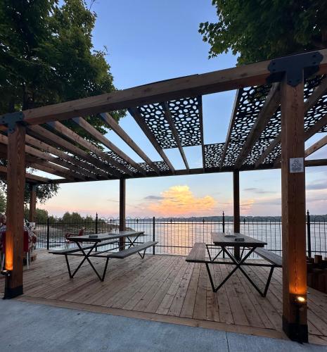 a wooden deck with two picnic tables on it at Goéliche hotel et appartement in Saint-Laurent-de-l'ile d'Orleans