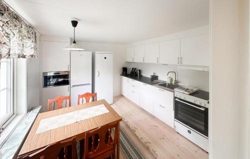 a kitchen with white cabinets and a wooden table at Holiday Home Möllstorpsgatan Färjestaden Ii in Färjestaden