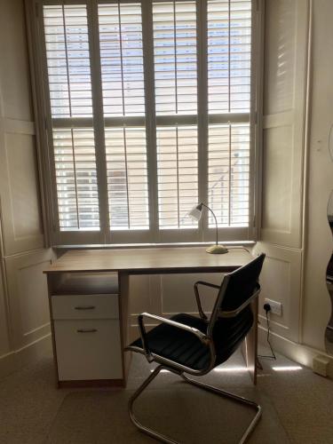 uma secretária com uma cadeira em frente a uma janela em Belgravia Apartments em Londres