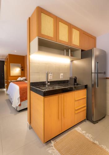 a kitchen with a sink and a refrigerator in a room at Loft com jacuzzi privativa frente mar do Bessa in João Pessoa