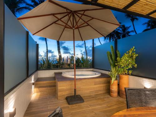an umbrella on a patio with a bath tub at Loft com jacuzzi privativa frente mar do Bessa in João Pessoa