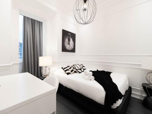 ein weißes Schlafzimmer mit einem Bett und einem Kronleuchter in der Unterkunft Akicity Santos Astoria in Lissabon