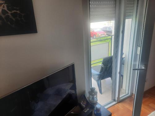 een woonkamer met een televisie en een stoel naast een raam bij Leo in Surčin