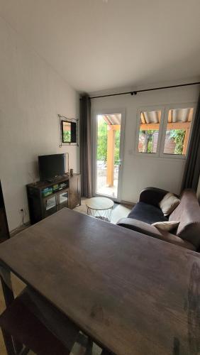 un salon avec une table et un canapé dans l'établissement Le petit chez nous Gîte climatisé jardin, à Pignans