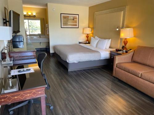 Quality Inn Alachua - Gainesville Area في ألاتشوا: غرفه فندقيه بسرير واريكه