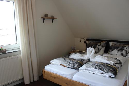 a bed with white blankets and pillows on it at Haus Deutsche Bucht in Borkum