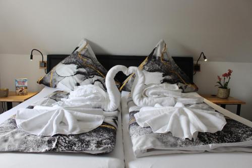 two white swans are sitting on a bed at Haus Deutsche Bucht in Borkum