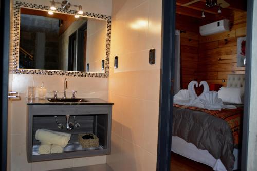 a bathroom with a sink and a mirror and a bed at Di Caro Cabañas Boutique in Colón