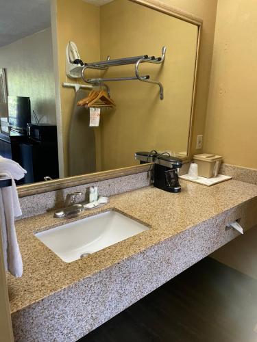 Quality Inn Alachua - Gainesville Area في ألاتشوا: منضدة الحمام مع الحوض والمرآة