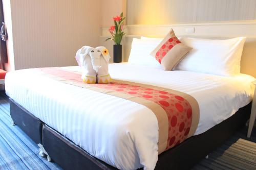uma cama grande com um elefante de peluche sentado nela em โรงแรมวีวิช V Wish Hotel em Khon Kaen