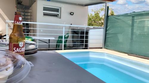 a bottle of beer sitting on a table next to a swimming pool at 3 bedrooms apartement with city view shared pool and enclosed garden at Feijo 5 km away from the beach in Almada