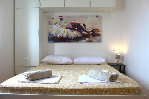 a bedroom with a bed with towels and a painting at Family apartments Jimmy - city center in Pag
