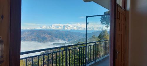 Habitación con balcón y vistas a las montañas. en Debuli's Home Stay, en Almora