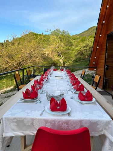 a long table with red chairs and plates and wine glasses at Ramona in Ambrolauri