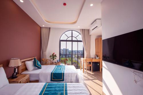 ein Hotelzimmer mit 2 Betten und einem großen Fenster in der Unterkunft L'AMANT Hotel in Sầm Sơn