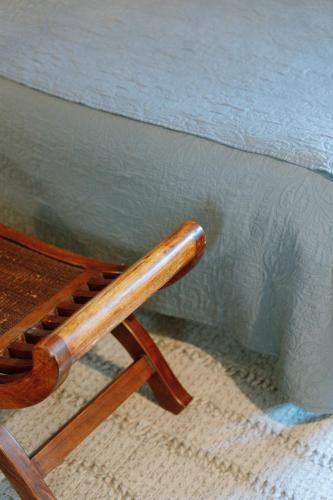 a wooden chair sitting next to a wall at Les Glycines de Monchy- Chambres d'hôtes in Monchy-Humières