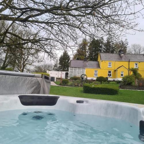 a swimming pool in a yard with a yellow house at Mill View Cottage at Pheasant Lane in Ráistín