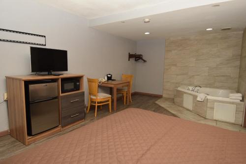 Cette chambre comprend une télévision et une salle de bains pourvue d'une baignoire. dans l'établissement University Manor Inn, à Buffalo