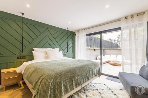 ein Schlafzimmer mit einem Bett und einer grünen Wand in der Unterkunft Le Jardin De Marie in Pontorson