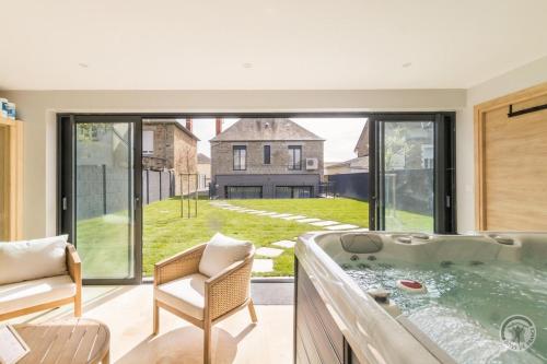 une grande baignoire dans un salon avec une fenêtre dans l'établissement Le Jardin De Marie, à Pontorson