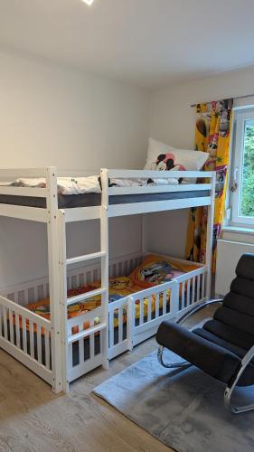two white bunk beds in a room with a chair at Kaufbeuren mit Wintergarten in Kaufbeuren