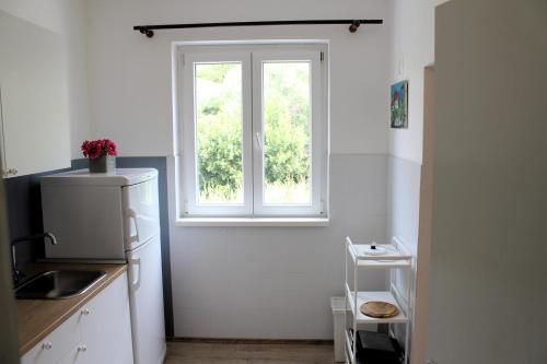 a kitchen with a window and a white refrigerator at Family apartments Jimmy - city center in Pag