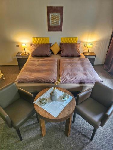 a bedroom with a large bed with two chairs and a table at MALEPARTUS in Bad Schwalbach