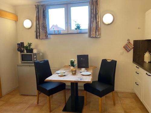 a small kitchen with a table and chairs and a microwave at Haus Deutsche Bucht in Borkum