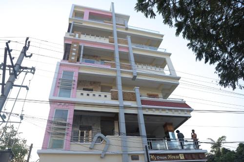 ein großes rosafarbenes Gebäude mit Leuten auf dem Balkon in der Unterkunft SBHS Neeladri Homestay in Tirupati