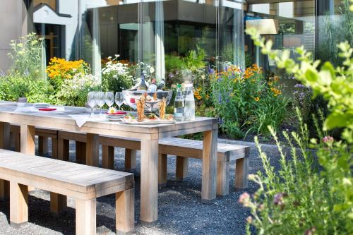 a wooden table and benches in a garden at Revier Hotel Säntispark in St. Gallen