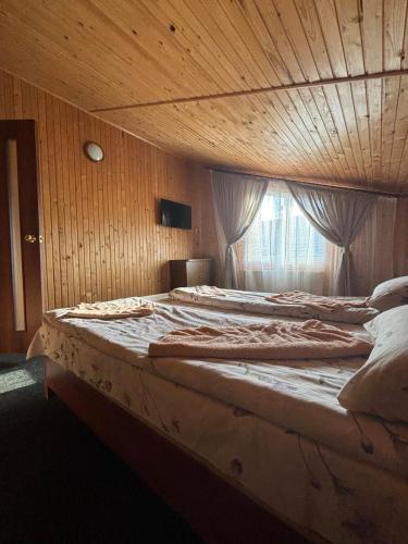 a large bed in a wooden room with a window at САДИБА та ЧАН "NA PAGORBI" in Yaremche