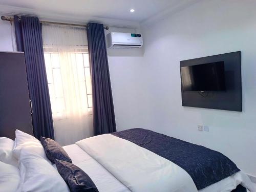 a bedroom with a bed and a tv on the wall at blueocean.cog Apartments in Benin City