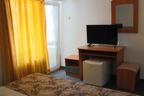 1 dormitorio con 1 cama y escritorio con TV en Guest House Elit en Burgas