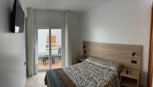 a bedroom with a bed and a view of a balcony at Hostal Juan Carlos in Carboneras