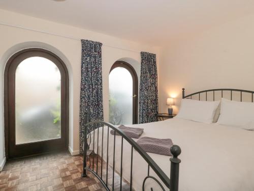 a bedroom with two large windows and a bed at The Cottage in Watchet