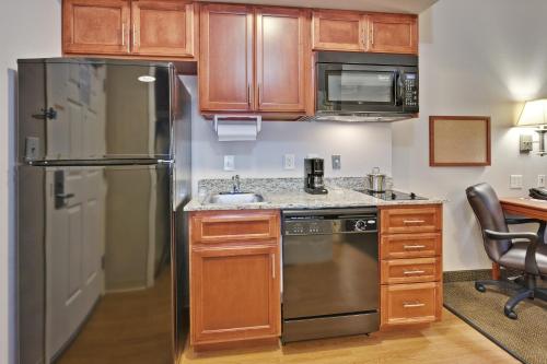 a kitchen with wooden cabinets and a stainless steel refrigerator at Candlewood Suites Murfreesboro by IHG in Murfreesboro