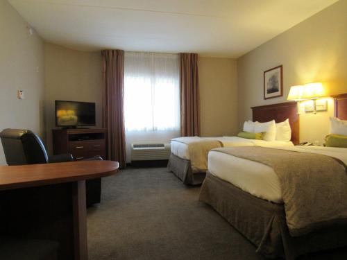 a hotel room with two beds and a television at Candlewood Suites Murfreesboro by IHG in Murfreesboro