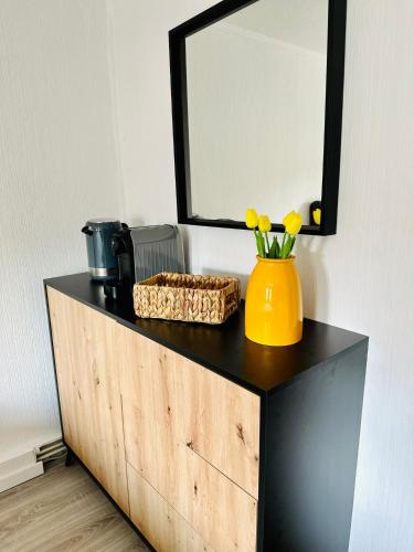 a dresser with a mirror and a yellow vase with flowers on it at Lous Ferienhaus 2 in Thale