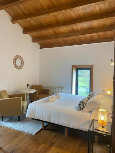 a bedroom with a large bed and a table and chairs at A Ribeira do Tambre in Troitosende