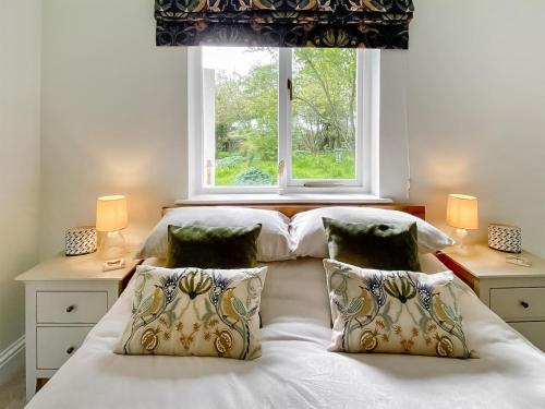 Rose Cottage في Blakemere: غرفة نوم بسريرين ونافذة