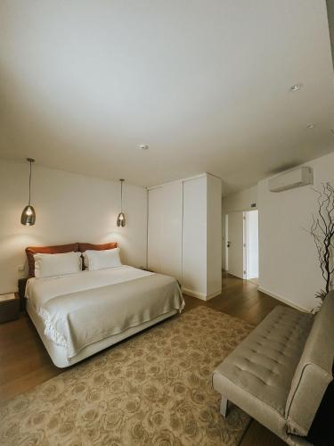 a bedroom with a large bed and a couch at Refúgio da Rainha in Moledo