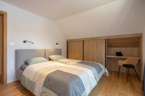 a bedroom with a large bed and a chair at House Natura Savica in Bohinj