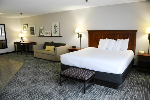 ein Hotelzimmer mit einem großen Bett und einem Stuhl in der Unterkunft Country Inn & Suites by Radisson, Fort Dodge, IA in Fort Dodge